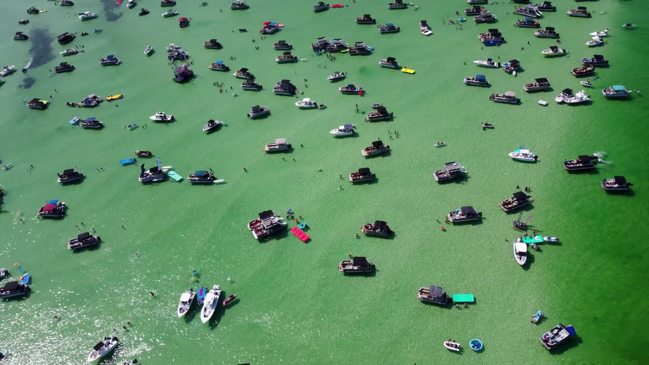 Aerial View of Crab Island Off of Destin Florida. Crowd of people at Crab Island in Destin, Florida during high tide with turquoise green clear water, busy pontoon boats, jet skis and boat party