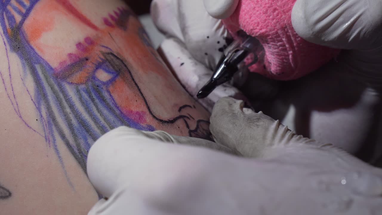 Tatuatore che realizza un tatuaggio del viso di una ragazza sulla pelle bianca, primo piano