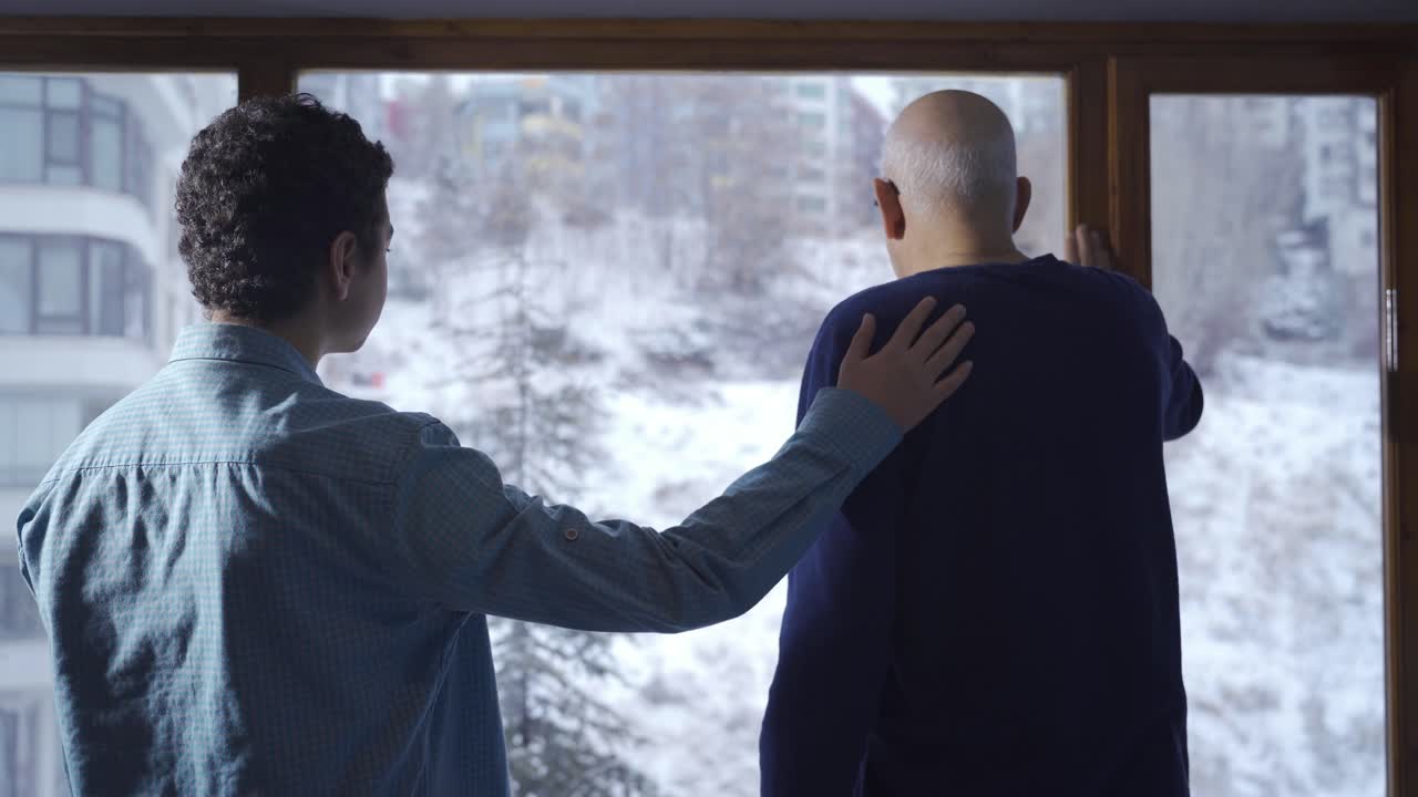 젊은이가 창문  ⁇ 에 있는 사려 깊고 우울한 할아버지를 격려합니다.