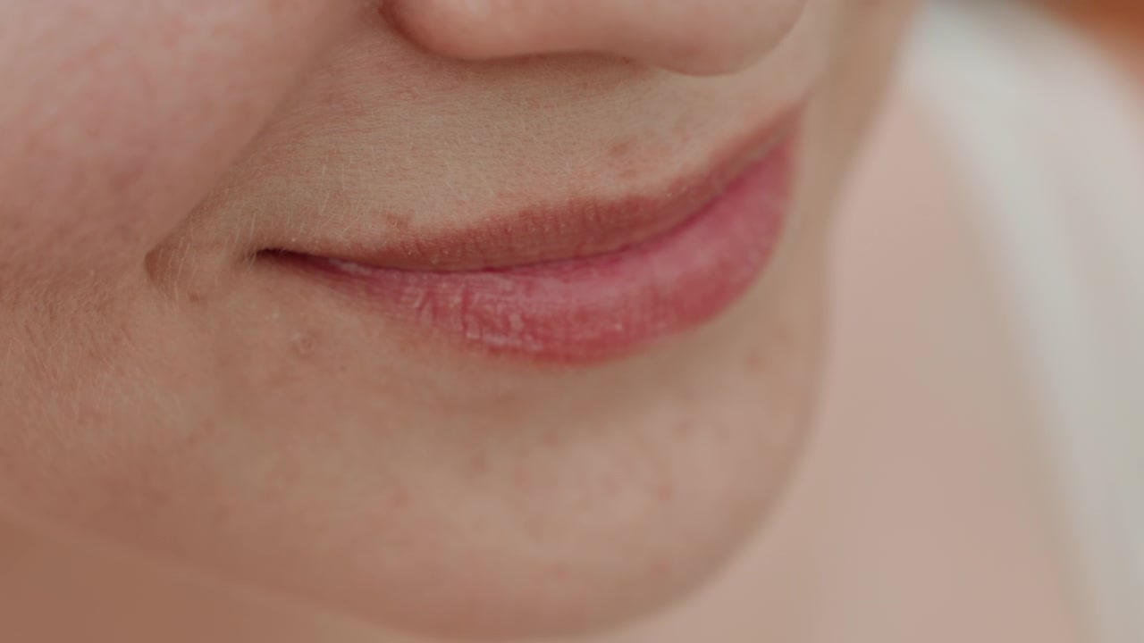 Close up view of woman lips as woman applies lip balm showing texture and movement involved in personal care. focus remains on her mouth area with soft lighting highlighting skin details
