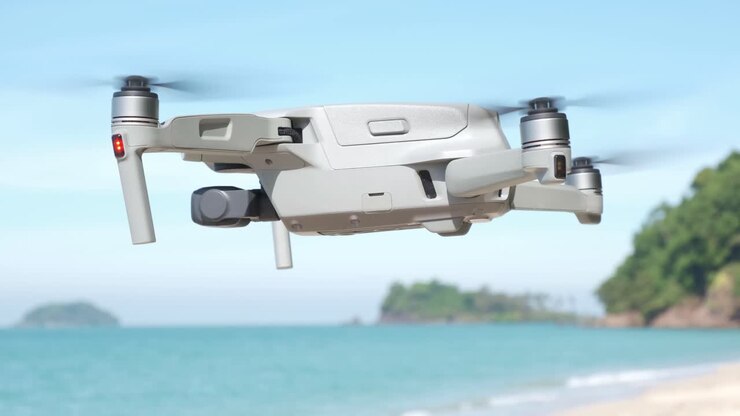 Drone che plana su una spiaggia con oceano e isole sullo sfondo.