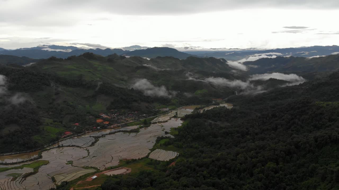 Filmato 4K ad alta quota di un volo su una splendida valle serena con risaie, che si inoltra in un paesaggio montuoso e boscoso nel Laos, Sud-est asiatico