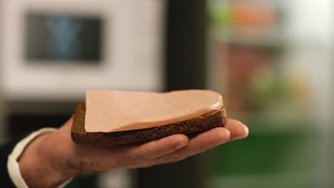 hand holding a slice of ham on a slice of bread