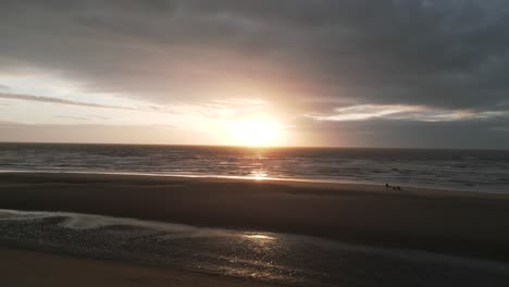 Dramatischer-Sonnenuntergang-über-Dem-Meer-Vom-Strand-Aus,-Schwenkaufnahmen-Von-Drohnen