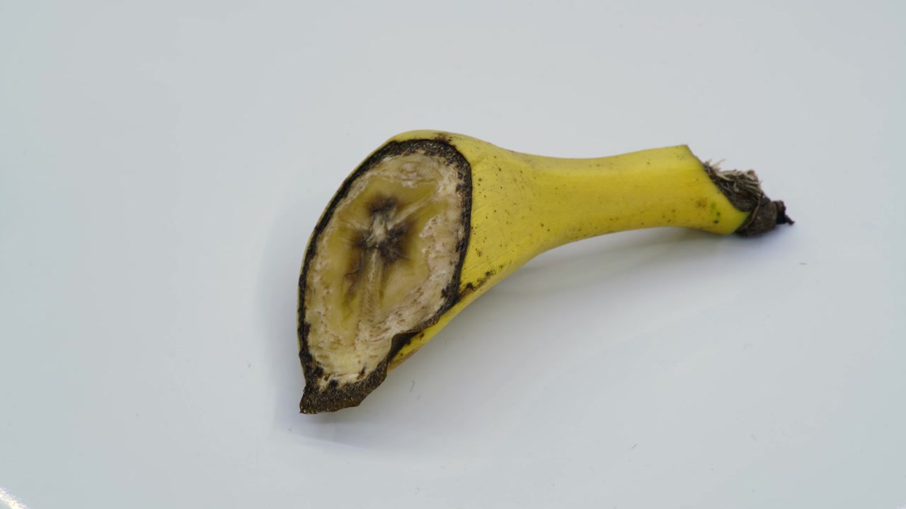 Pokrojony kawałek banana utleniający się na białym tle.
