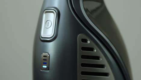 vertical vacuum cleaner during charging, close-up of power button and 4-stage battery indicator