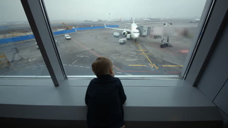 little boy looking out the window at airport