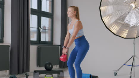 una joven y hermosa mujer caucásica entrenando con pesas en el estudio de gimnasio privado