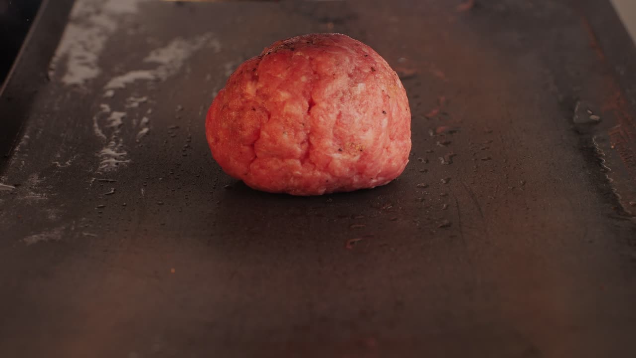 Cooking American fat smash burger on grill close-up. Beef or pork cutlet smashing by burger press. The chef in kitchen of the restaurant making cutlets for burgers - smash burger beefsteak. Fast and street food concept. High quality 4k footage