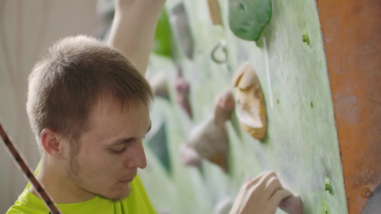 escalador de rocas hombre haciendo ejercicio en la pared del gimnasio de escalada interior. entrenando escaladores en la parede de escalada. hombre atlético tiene entrenamiento de escalada en roca en el gimnasio deportivo.