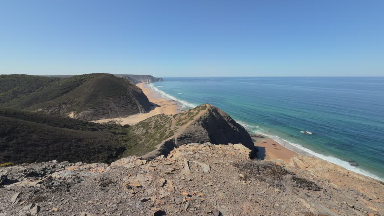 Panoramaudsigt over en barsk kystlinje med sandstrande og blåt hav