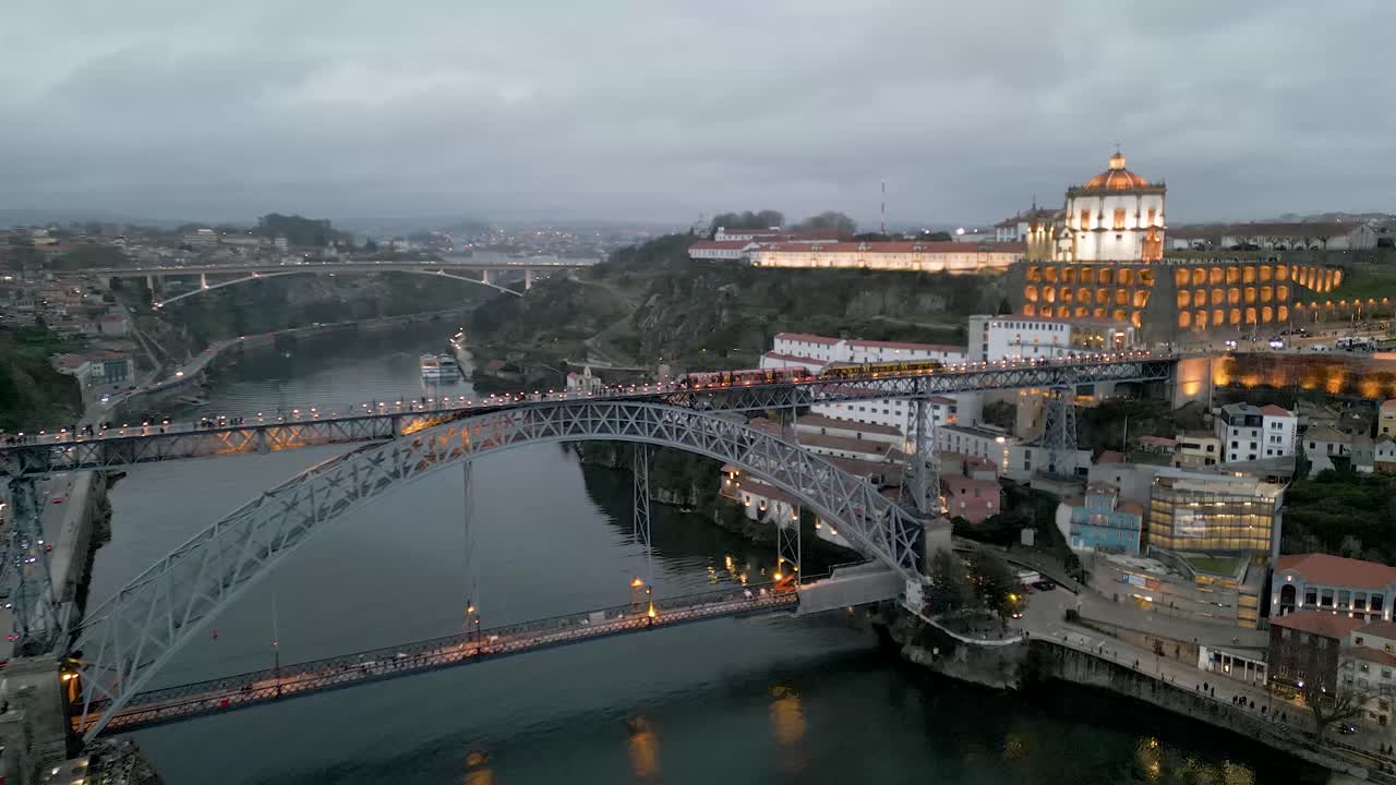 Aerial tracking shot of a tram driving over the Dom Lu&iacute;s I Bridge with stunning architecture