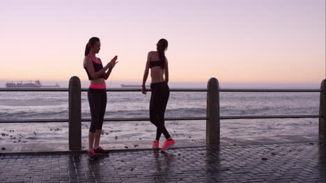 dos amigos atléticos estirándose antes de una carrera en el paseo marítimo al atardecer