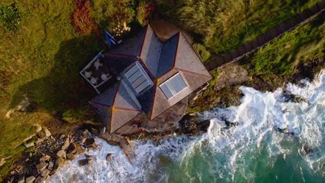 cornish house on a cliff overlooking ocean waves with a top down drone view from above, cornwall, england, uk