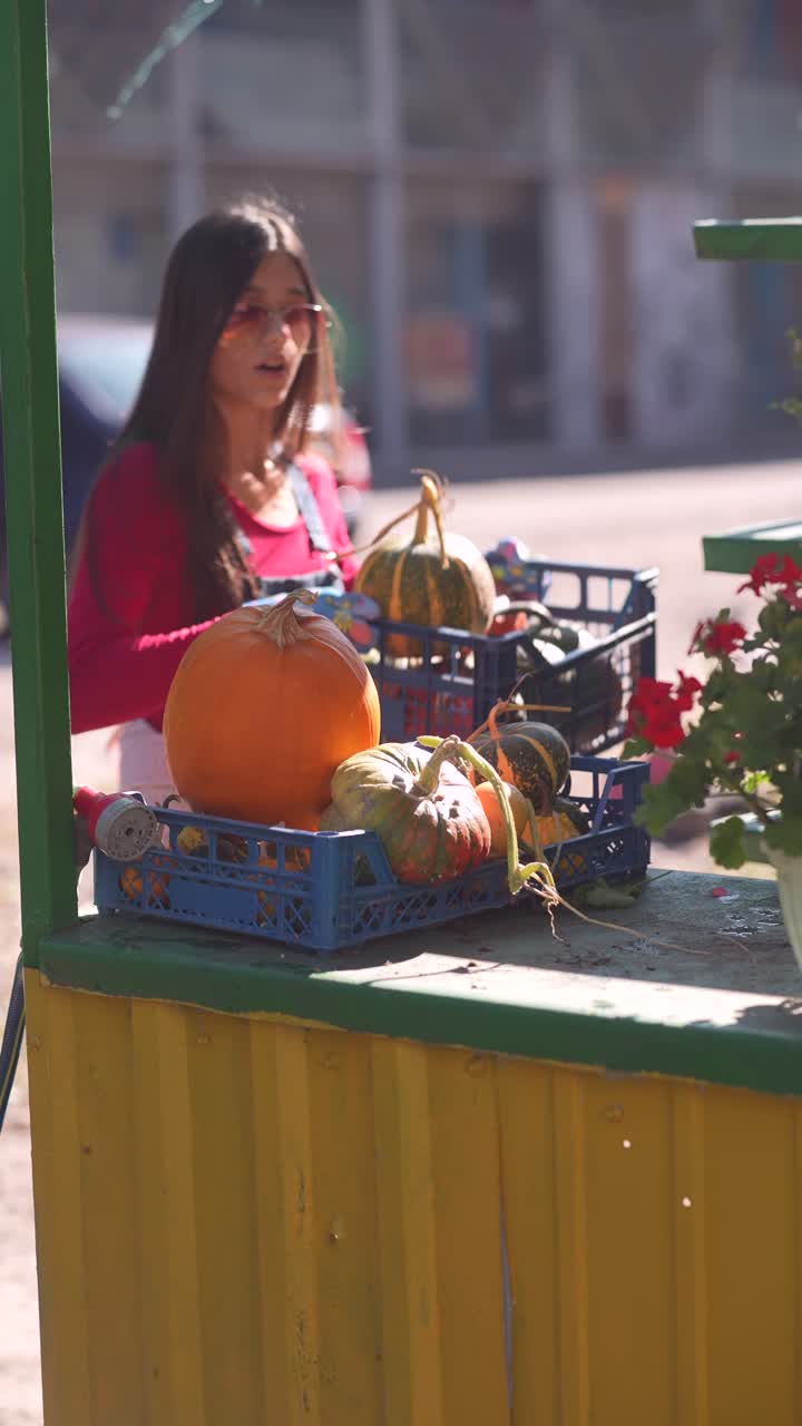 mujer vendiendo calabazas y flores en un mercado callejero