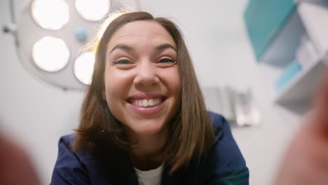 Portrait-first-person-view-of-a-happy-brunette-veterinarian-girl-in-a-blue-uniform-holds-a-pet-in-her-hands-during-an-examination-in-a-veterinary-clinic-and-smiles-broadly-at-it