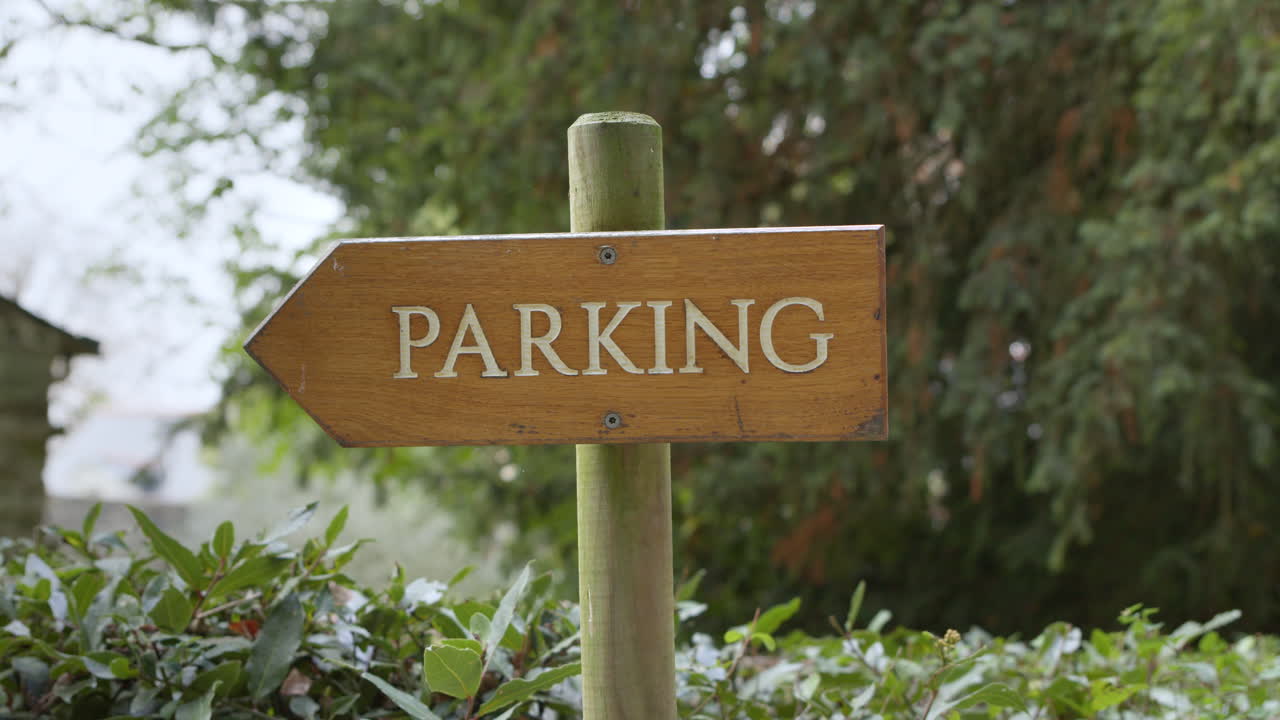 Close up pan right shot of wooden parking sign in countryside