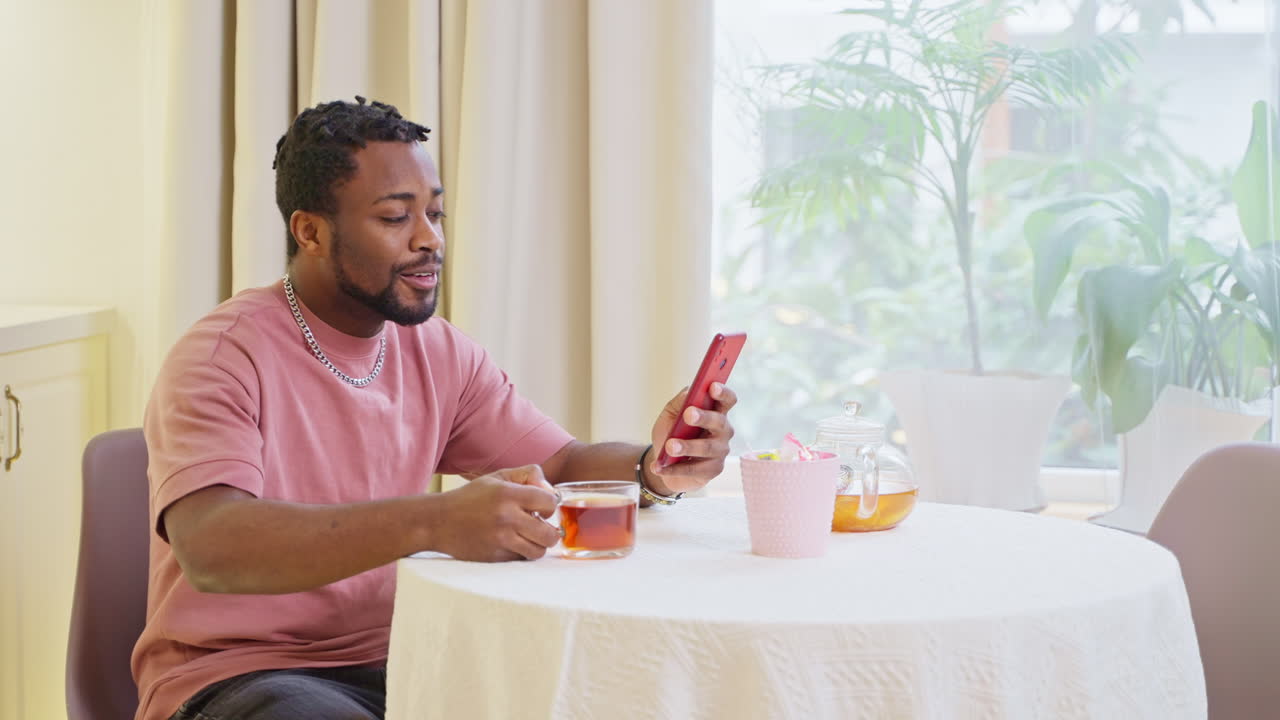 Man Drinking Tea and Using Mobile Phone at Home