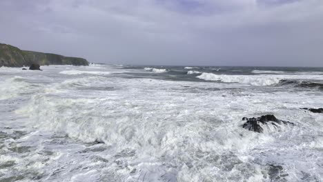 les vagues de tempête s'écrasent contre les falaises du sol, provoquant une érosion rapide. tempête de printemps sur la côte du cuivre, waterford, irlande.