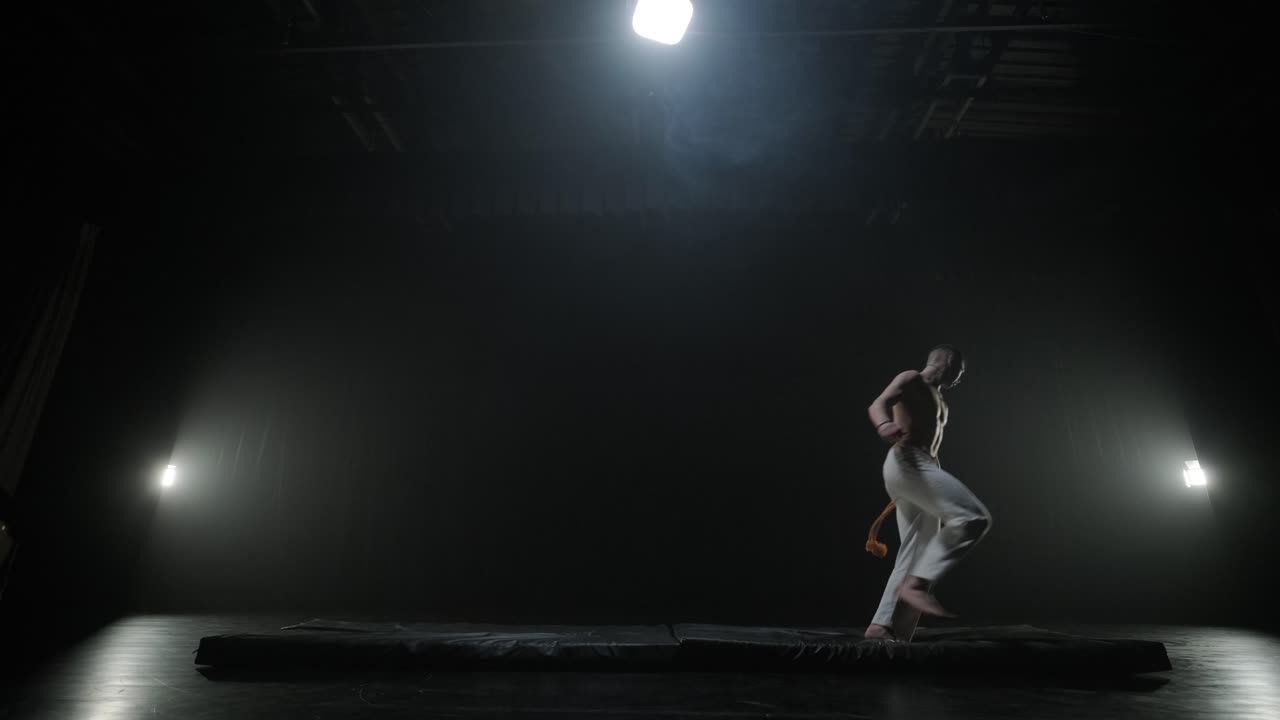 무대에서 역동적인 움직임을 보이는 카포에라 싸움, 무술, 춤, 액션 아크로바틱스, 스포트라이트 아래에서 힘, 유연성 및 기법을 보여주는 벌거벗은 가 운동선수