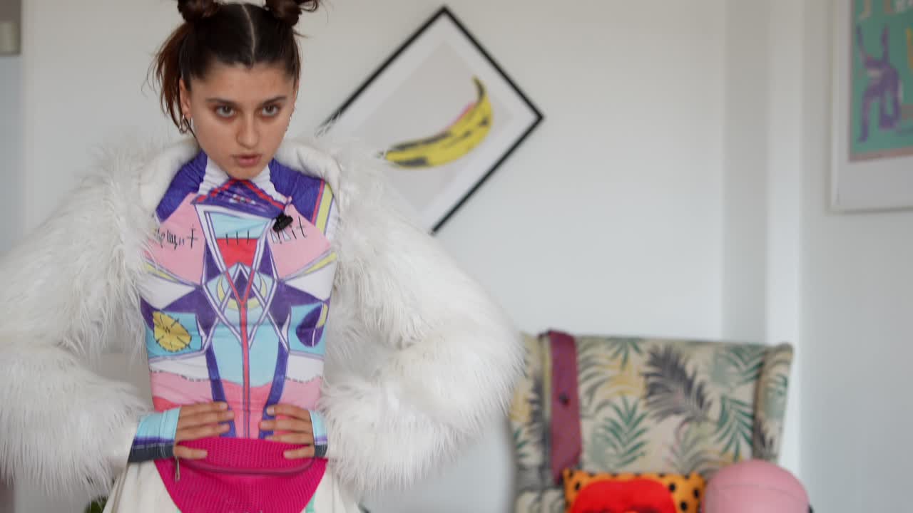 Mujer joven elegante posando con un atuendo de moda único y colorido.