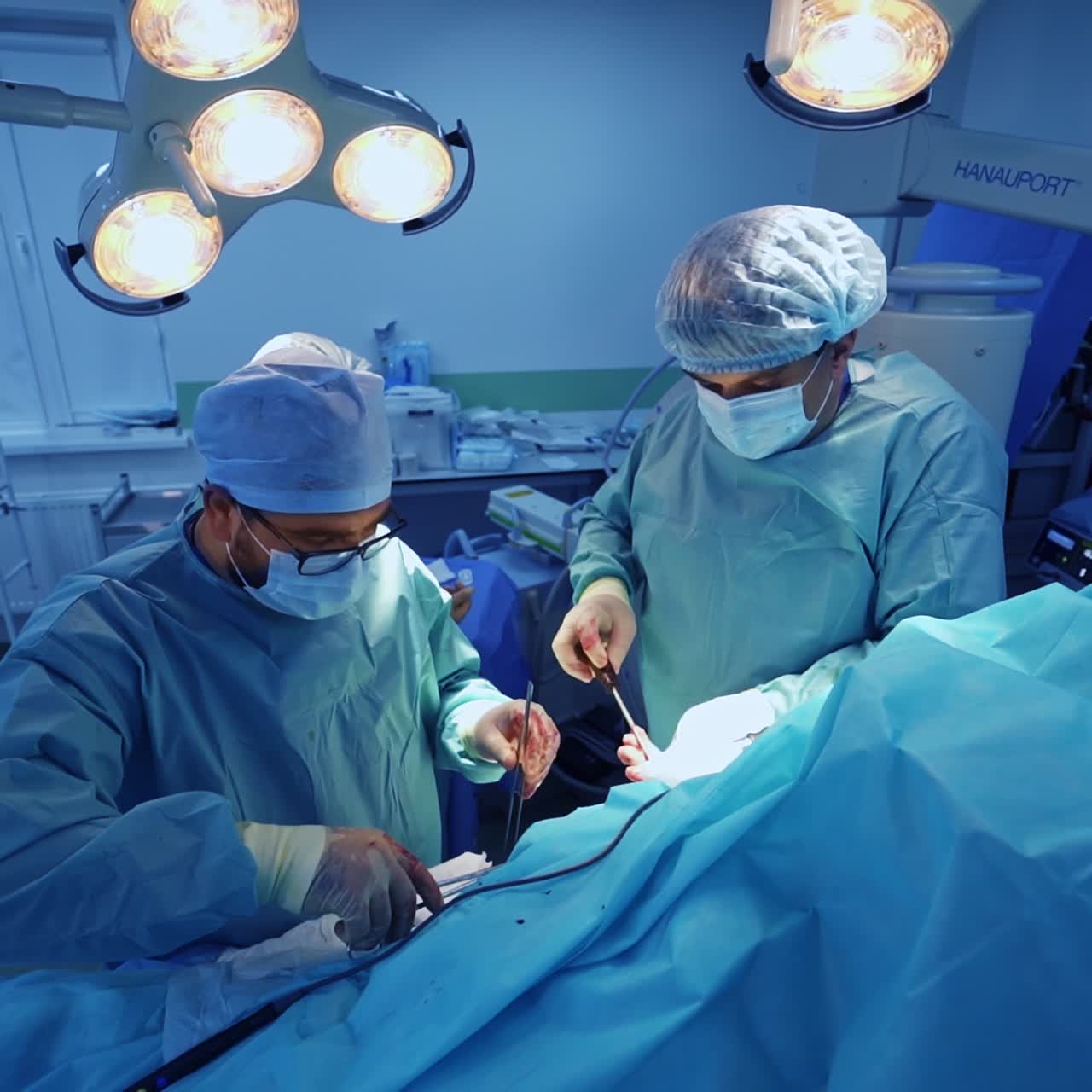 Two surgery professionals operating the patient covered with sheet. Medics using the metal tools in trauma treating