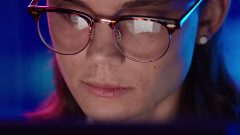 close up portrait young business woman working late using tablet computer browsing financial graph data looking at information on screen wearing glasses