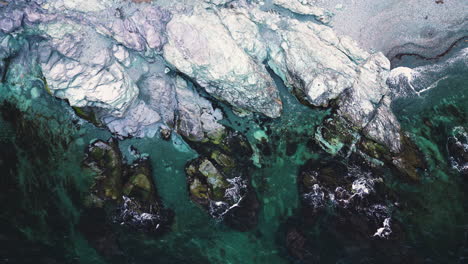 las olas de las corrientes oceánicas se rompen en la costa rocosa con rocas cubiertas de algas en newport