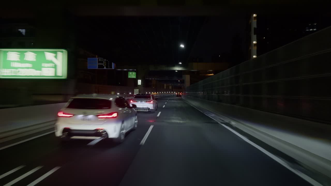 Night Lights of Tokyo’s Expanding Suburbs See Tokyo’s new territories unfold through the car's front view, where city lights and highway lanes create a mesmerizing scene