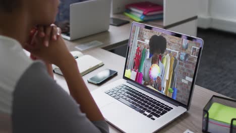 mid section of african american woman having a video call with female colleague on laptop at office