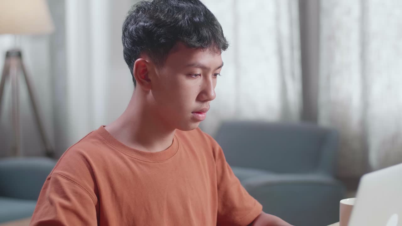 아시안 소년 신발 디자이너가 집에서 노트북으로 일하면서 두통을 고 있습니다.