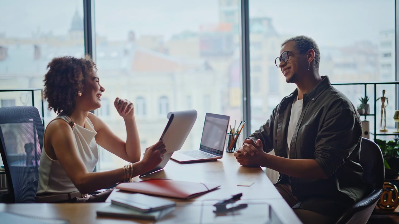 Colleagues discussing project in office meeting, woman presenting papers to man