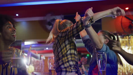 video de un grupo diverso de amigos felices bebiendo y viendo juegos deportivos en un bar, celebrando