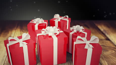 animación de nieve cayendo sobre los regalos de navidad sobre un fondo de madera y negro