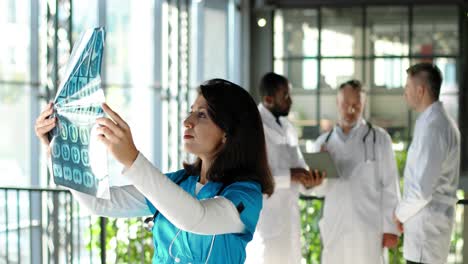 hermosa doctora sosteniendo rayos x y examinándolos en el hospital