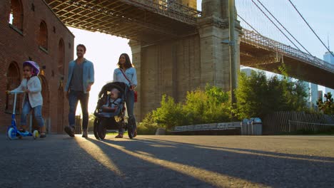 young family with two kids walking under bridge in manhattan