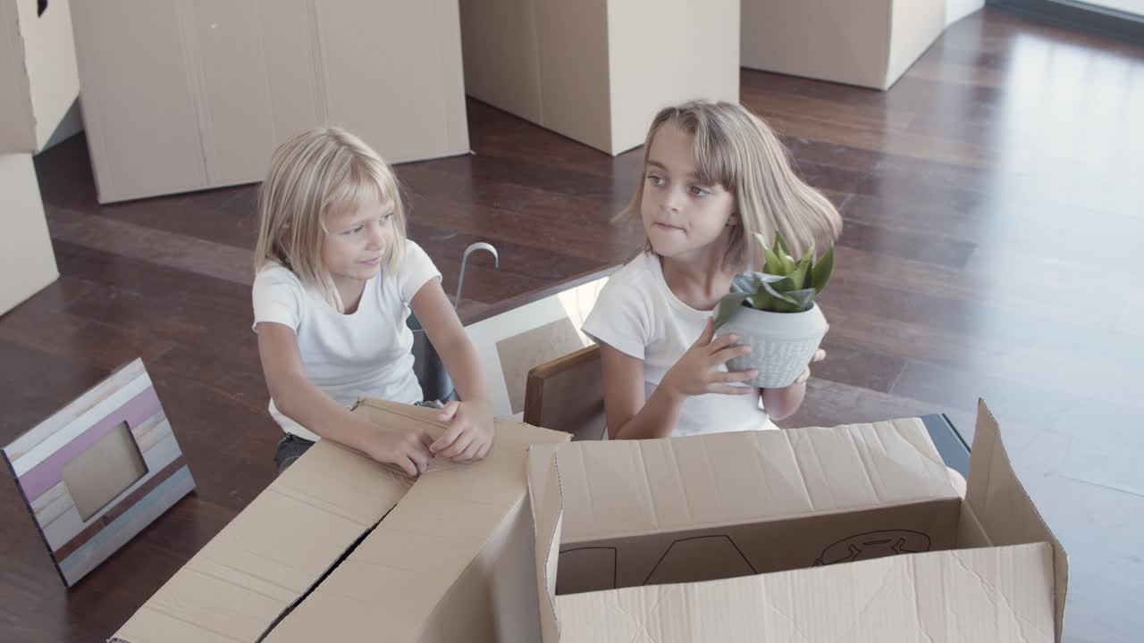 hermanas pequeñas desempaquetando cosas en un nuevo apartamento