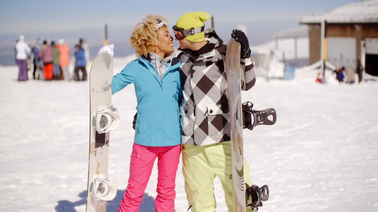 una pareja joven y amorosa con sus snowboards.