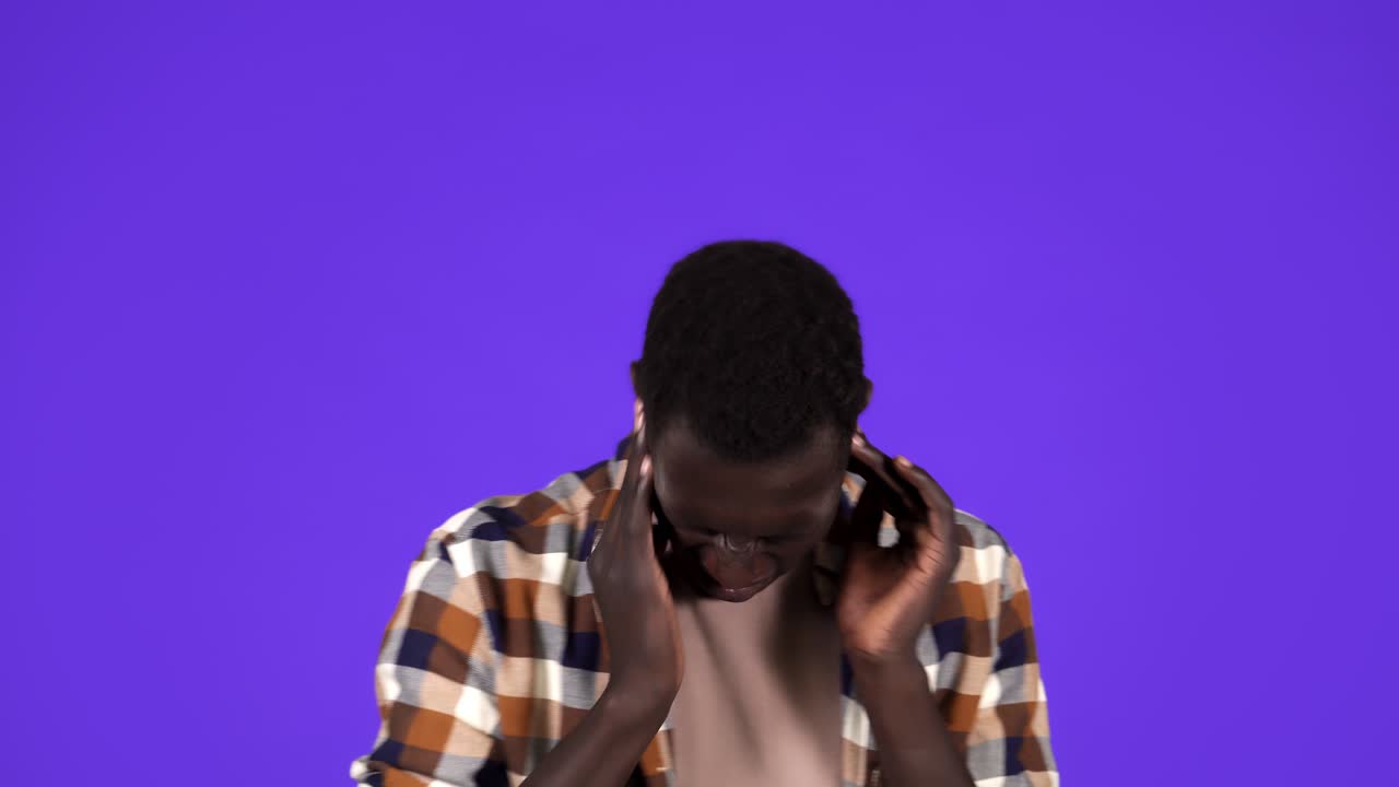Uomo afroamericano soddisfatto si gode un suono potente e perfetto nelle nuove cuffie, vestito con una camicia a quadri, ha tempo libero e si diverte.