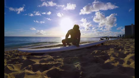 surfer with a surfboard sitting on the beach 4k