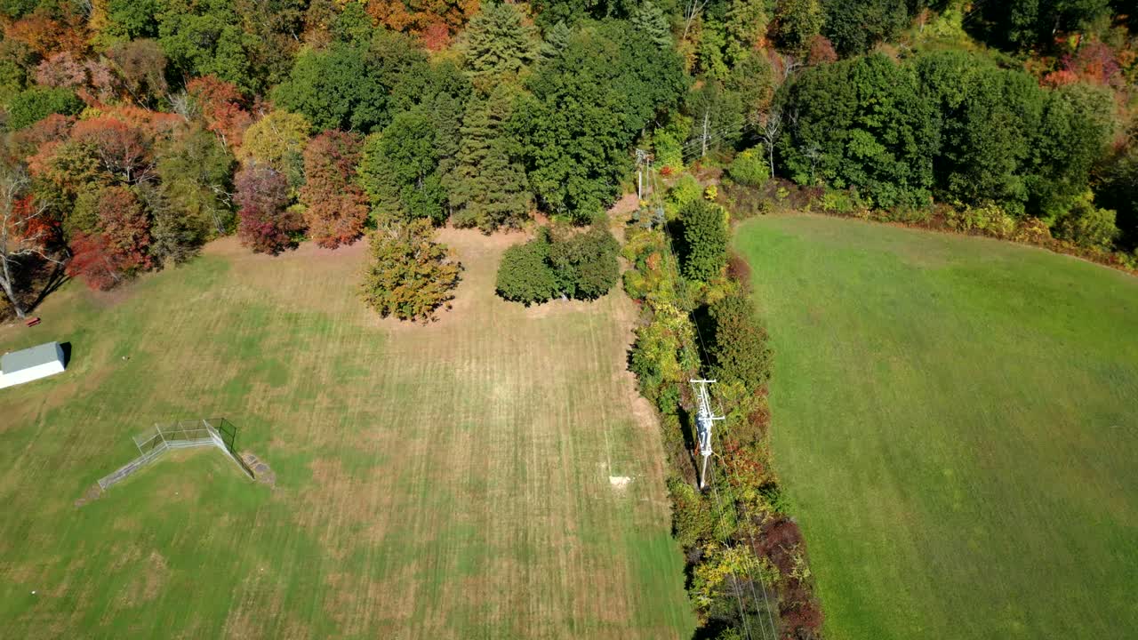 Aerial view of dense forest space of Groff Park in early autumn with colorful foliage and open meadow, Amherst, Massachusetts, USA
