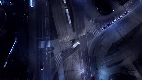 vista aérea nocturna vertical coches de tráfico en la intersección y luces de la calle y calles iluminadas en una ciudad moderna. avión no tripulado de tráfico.