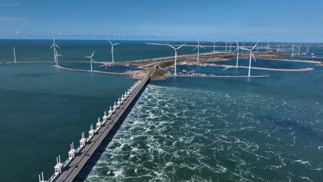 Toma-Aérea-De-Drones-De-La-Barrera-De-Marejada-De-Oosterschelde-Con-Parque-Eólico-De-Energía-Verde-En-El-Fondo