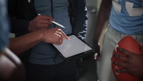 Football team strategizing with a tablet