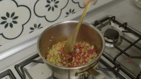 stirring minced meat, vegetables and tomato paste in cooking pot