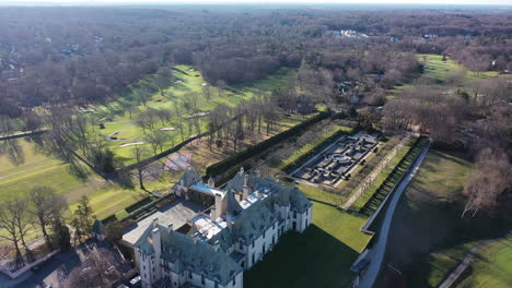 an aerial view over an upscale, luxury mansion with an eight reflection pool fountain, on long island, ny