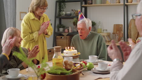 Älterer-Mann-Bläst-Kerzen-Auf-Kuchen-Bei-Geburtstags-Dinnerparty