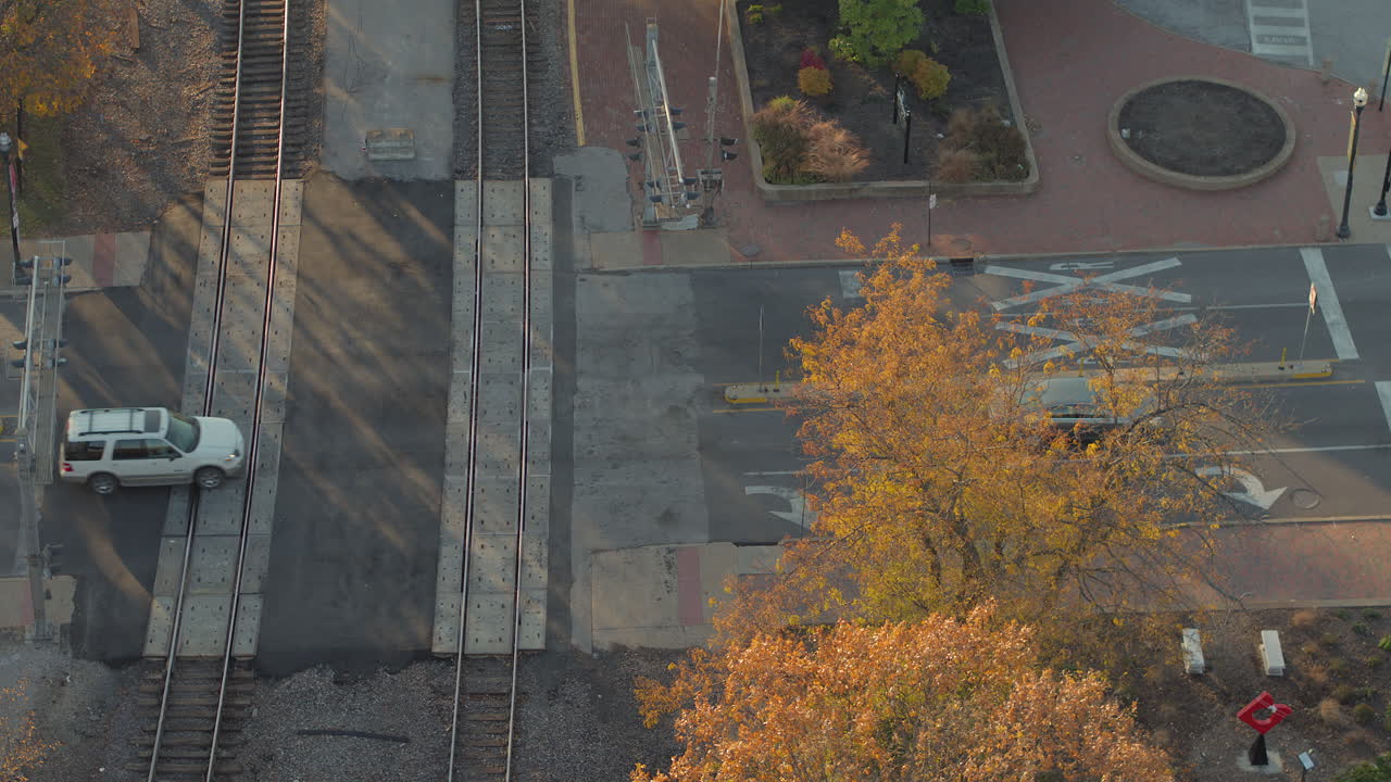вид сверху на автомобили, пересекающие железнодорожные пути на перекрестке в кирквуде, штат миссури, осенью в золотой час