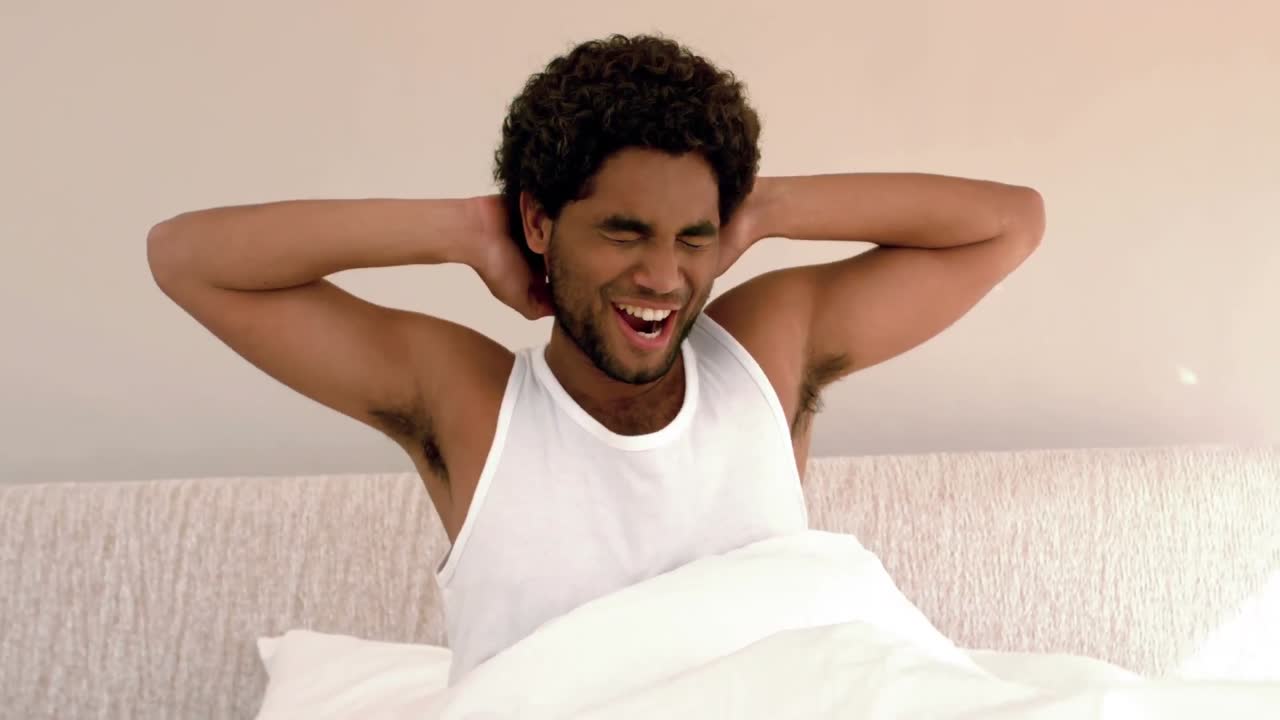 Uomo che si sveglia e si stira a letto.