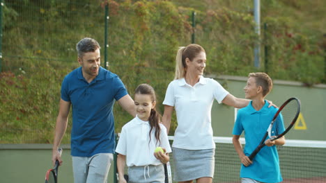 Happy-Family-Leaving-The-Court-Together-After-Playing-Tennis-On-A-Summer-Day